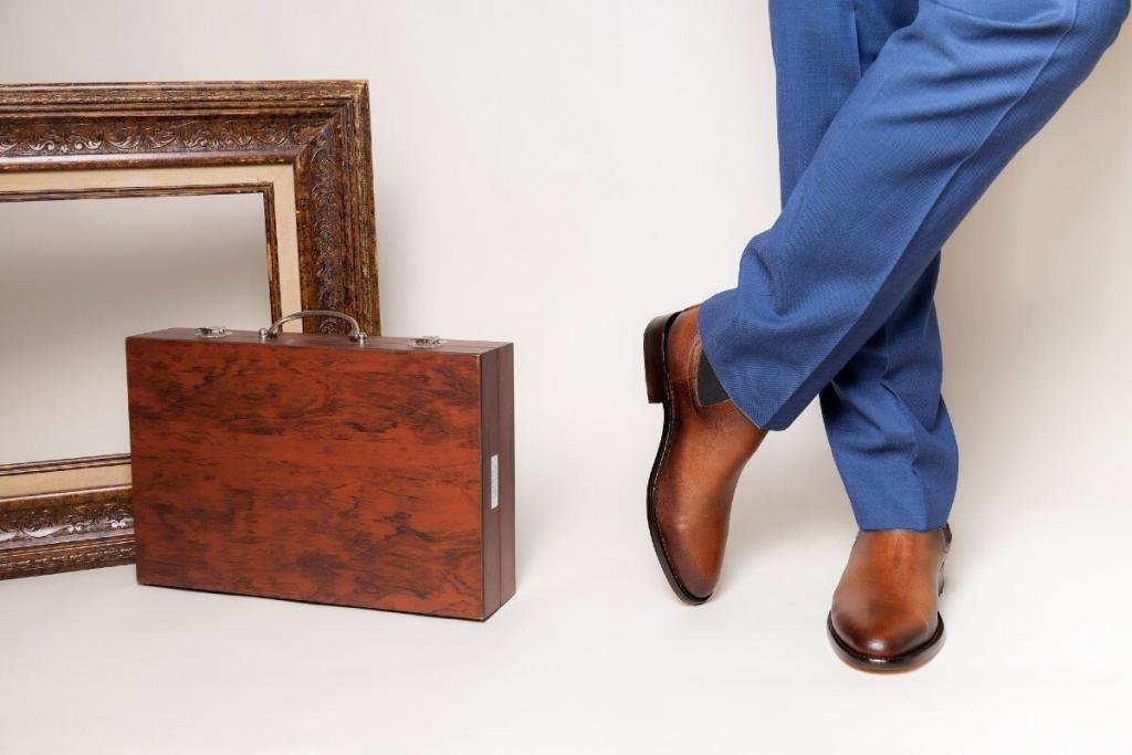 Botas Chelsea de piel café para hombre combinadas con pantalón de vestir azul en un look formal