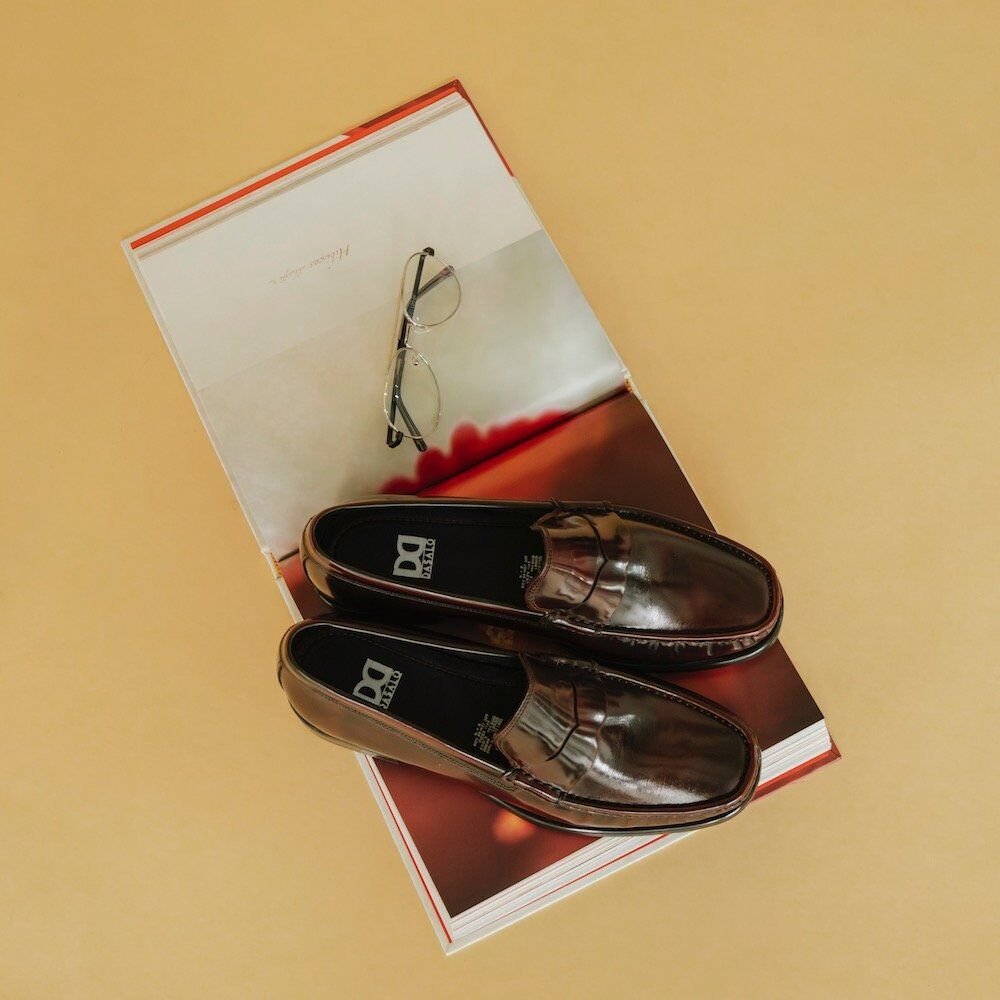 Penny Loafer De Piel Vacuno Camaleón Vino Estilo Clásico Sobre Libro Abierto En Fotografía Editorial