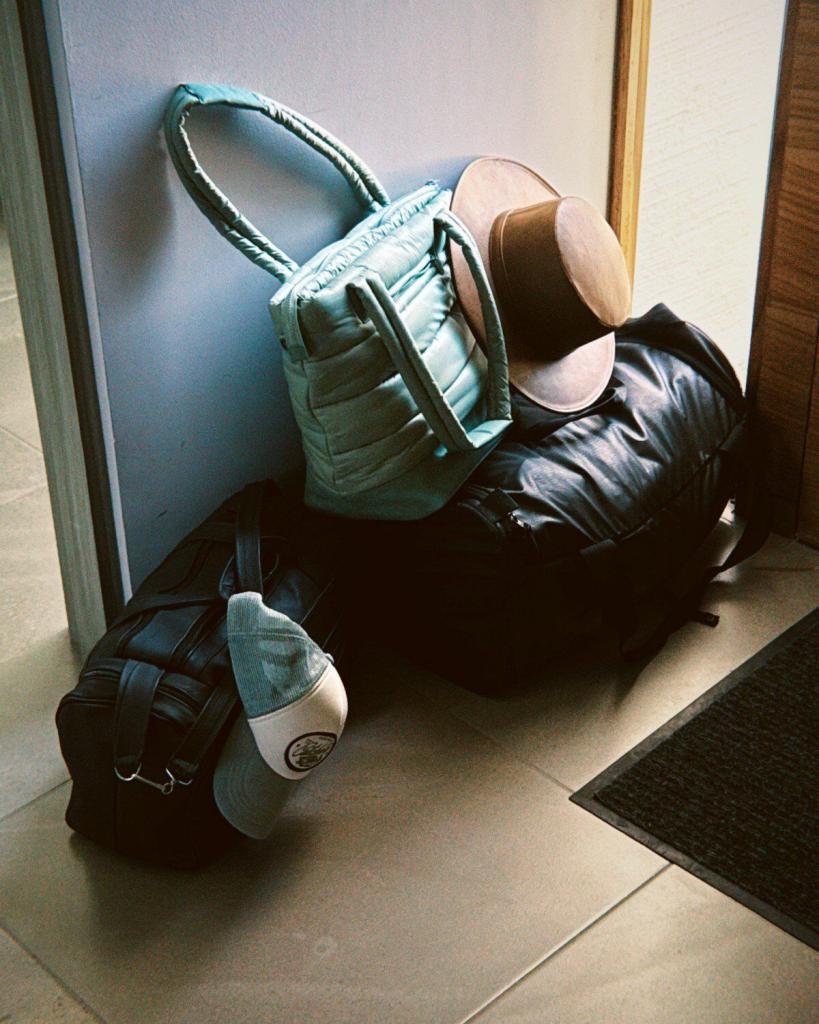 Equipaje ligero con maleta de piel, bolso y sombrero, ideal para viajar en clima cálido con estilo y practicidad