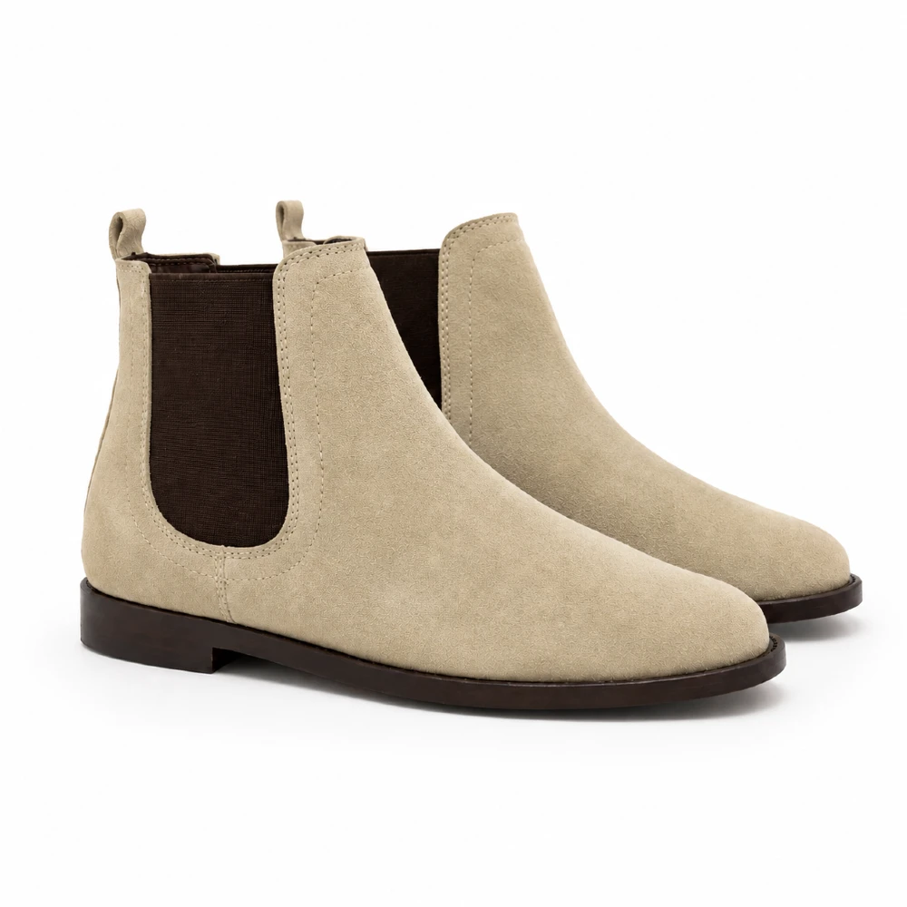 Par de botines chelsea de gamuza arena para hombre con elásticos café oscuro y suela de cuero.
