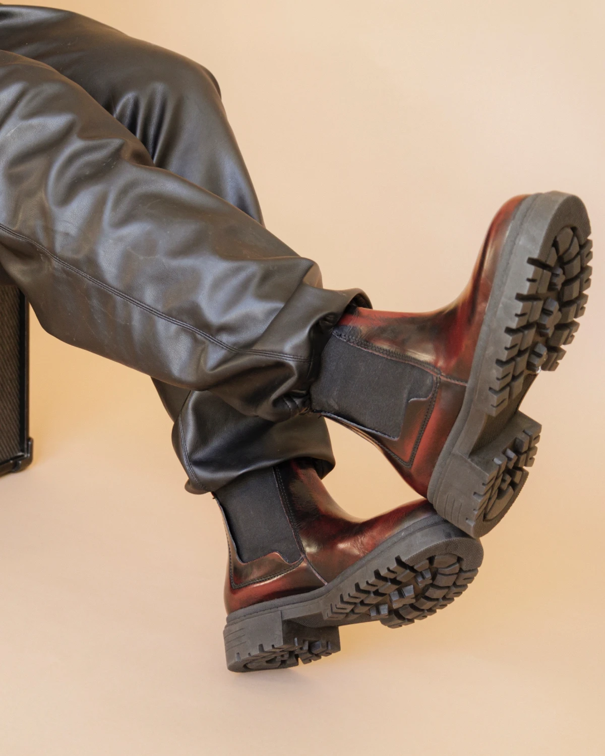 Botines Chelsea color vino combinados con pantalón negro de efecto piel.