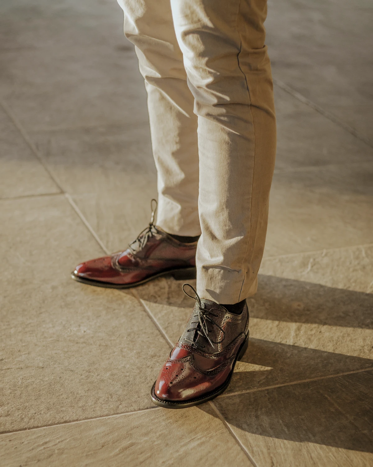 Hombre usando zapatos bostonianos color vino con pantalón beige en un outfit elegante.