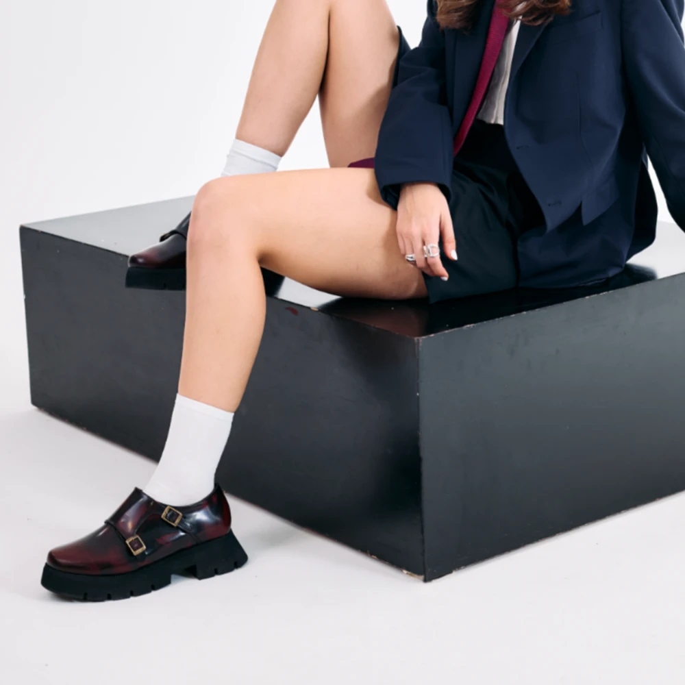 Zapato chunky para mujer en piel vino con doble hebilla metálica y suela gruesa negra, mostrado de perfil.