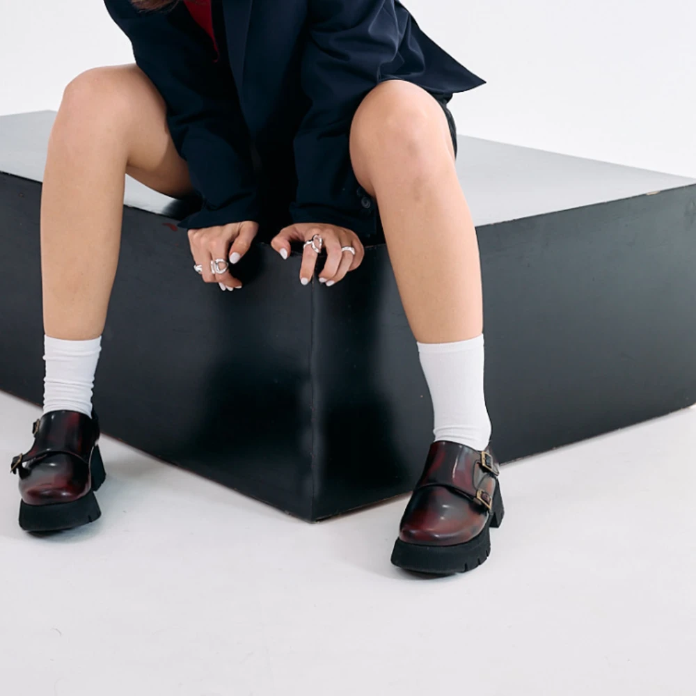 Zapatos monkstrap para mujer en piel color vino con doble hebilla y suela chunky negra, vistos en ambos pies.