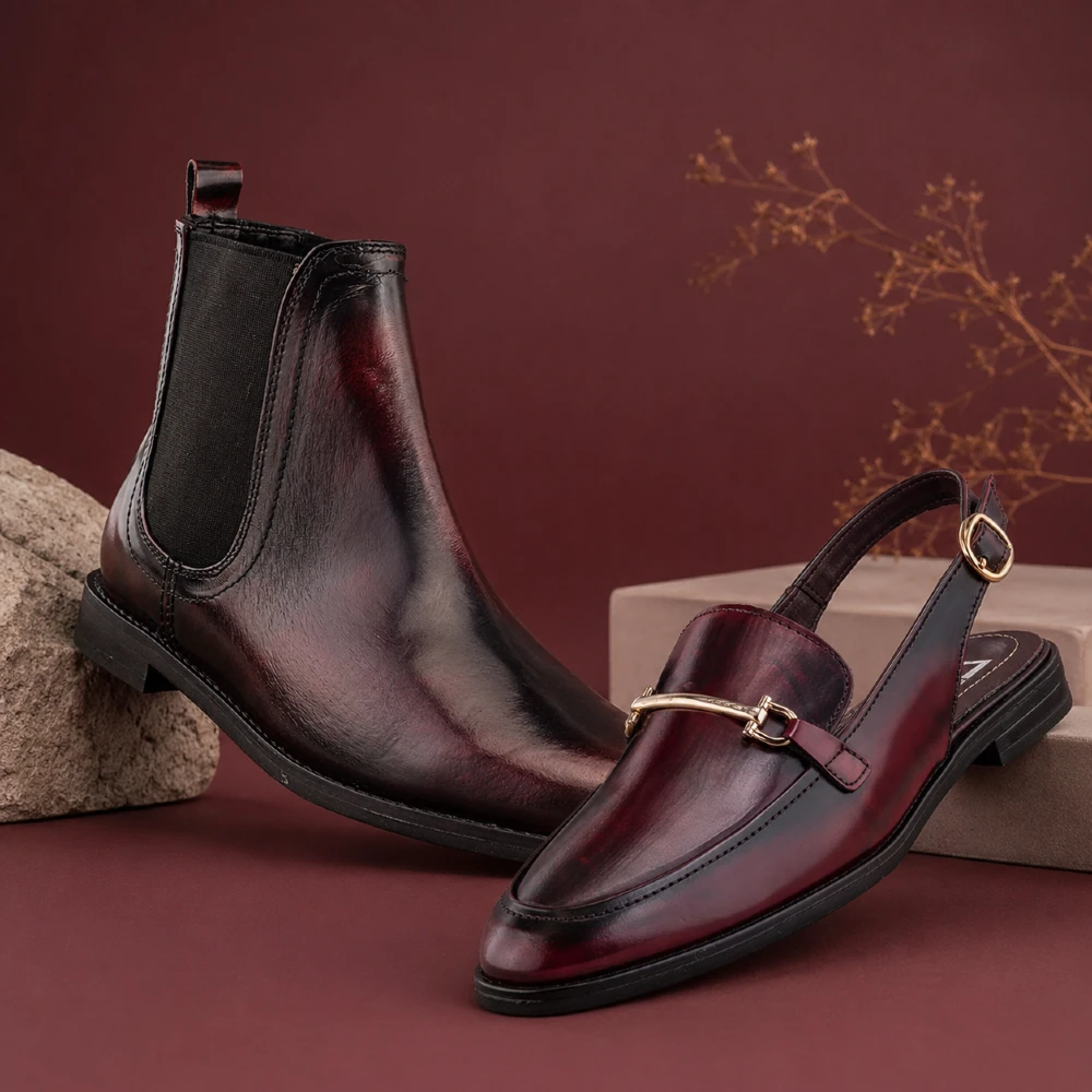 Botín Chelsea para hombre y mocasín destalonado para mujer en color vino camaleón sobre fondo editorial.