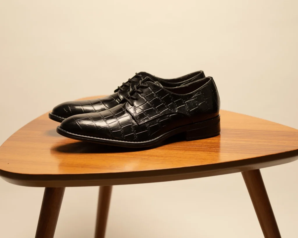 Zapato derby negro con grabado reptil y suela regular, ejemplo de zapatos modernos de vestir para combinar en la oficina o fin de semana.