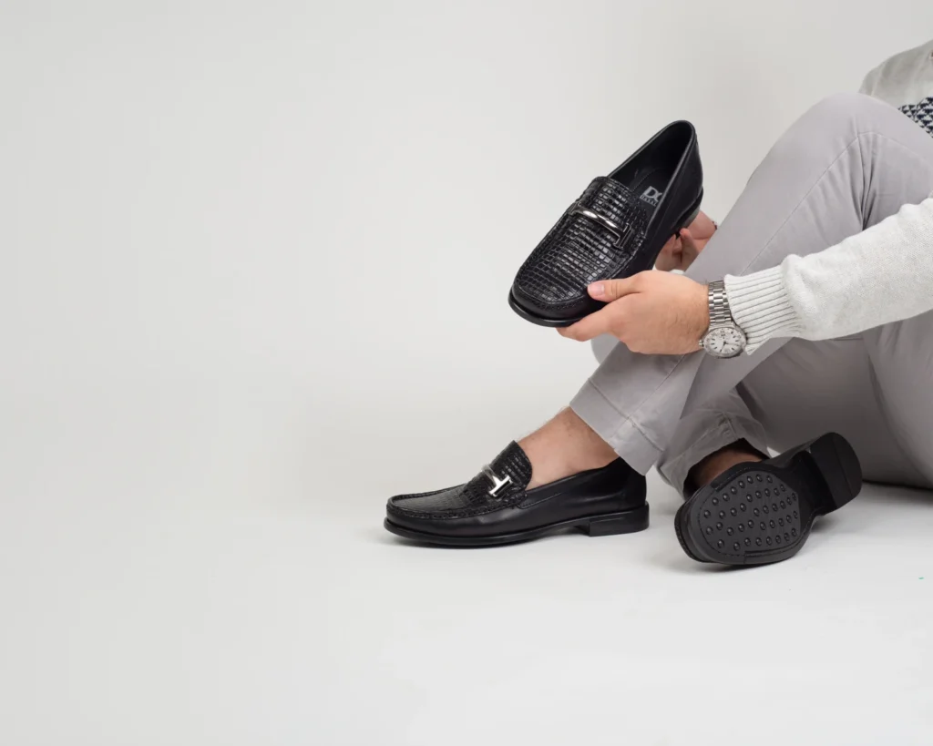 Loafers negros con detalle metallico combinados con pantalon gris, la mejor opcion de zapatos modernos de vestir para un look business casual.